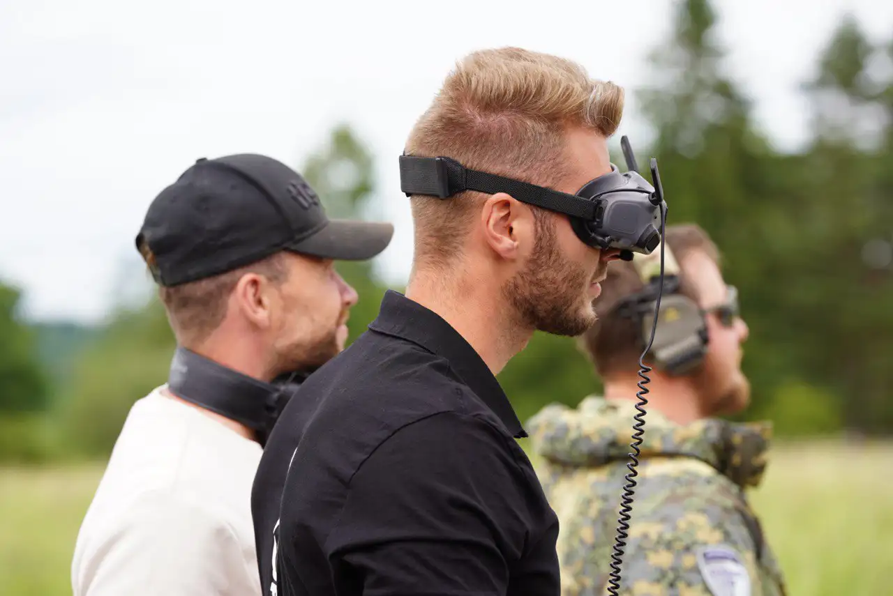 Skypassion FPV Pilot mit FPV-Brille beim professionellen Outdoor-Einsatz – Drohnenproduktion im Team